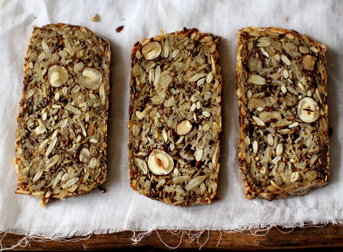 A loaf of healthy bread with seeds on a wooden cutting board.