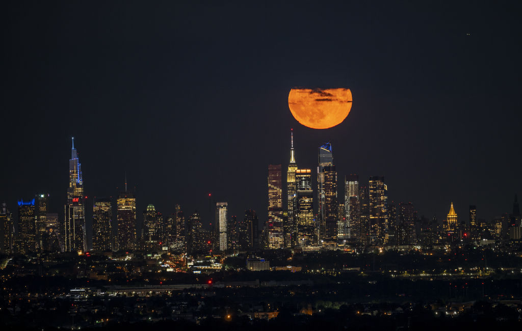 Orange supermoon rising above the Empire State Building in New York City.